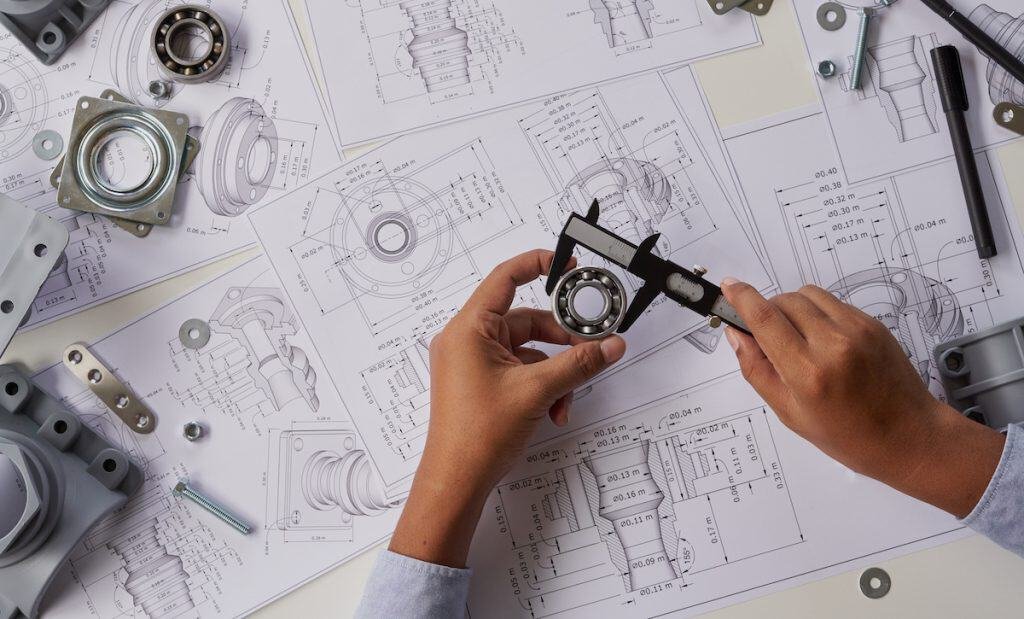 engineer technician designing drawings mechanical parts engineering engine manufacturing factory industry industrial work project blueprints measuring bearings caliper tools